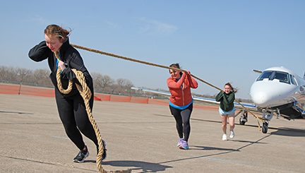 3 people pulling an airplane on a tow line