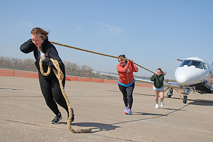 3 people pulling an airplane on a tow line