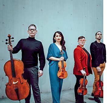 A string quartet stands with their instruments