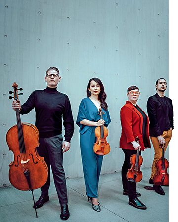 A string quartet stands with their instruments