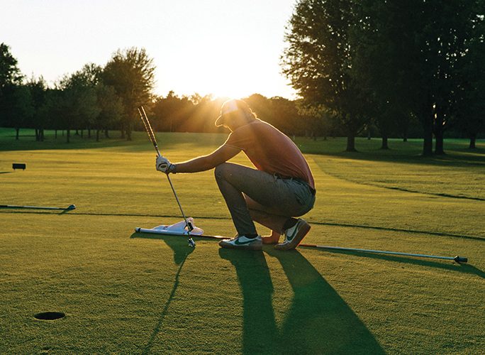 a man crouches on the golf green