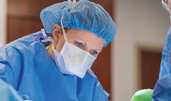 a surgeon operating in blue scrubs