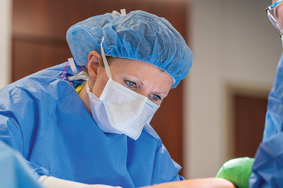 a surgeon operating in blue scrubs