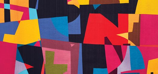 A photo of a large, irregular, brightly coloured, geometric quilt