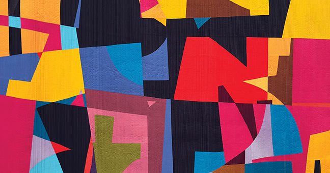 A photo of a large, irregular, brightly coloured, geometric quilt